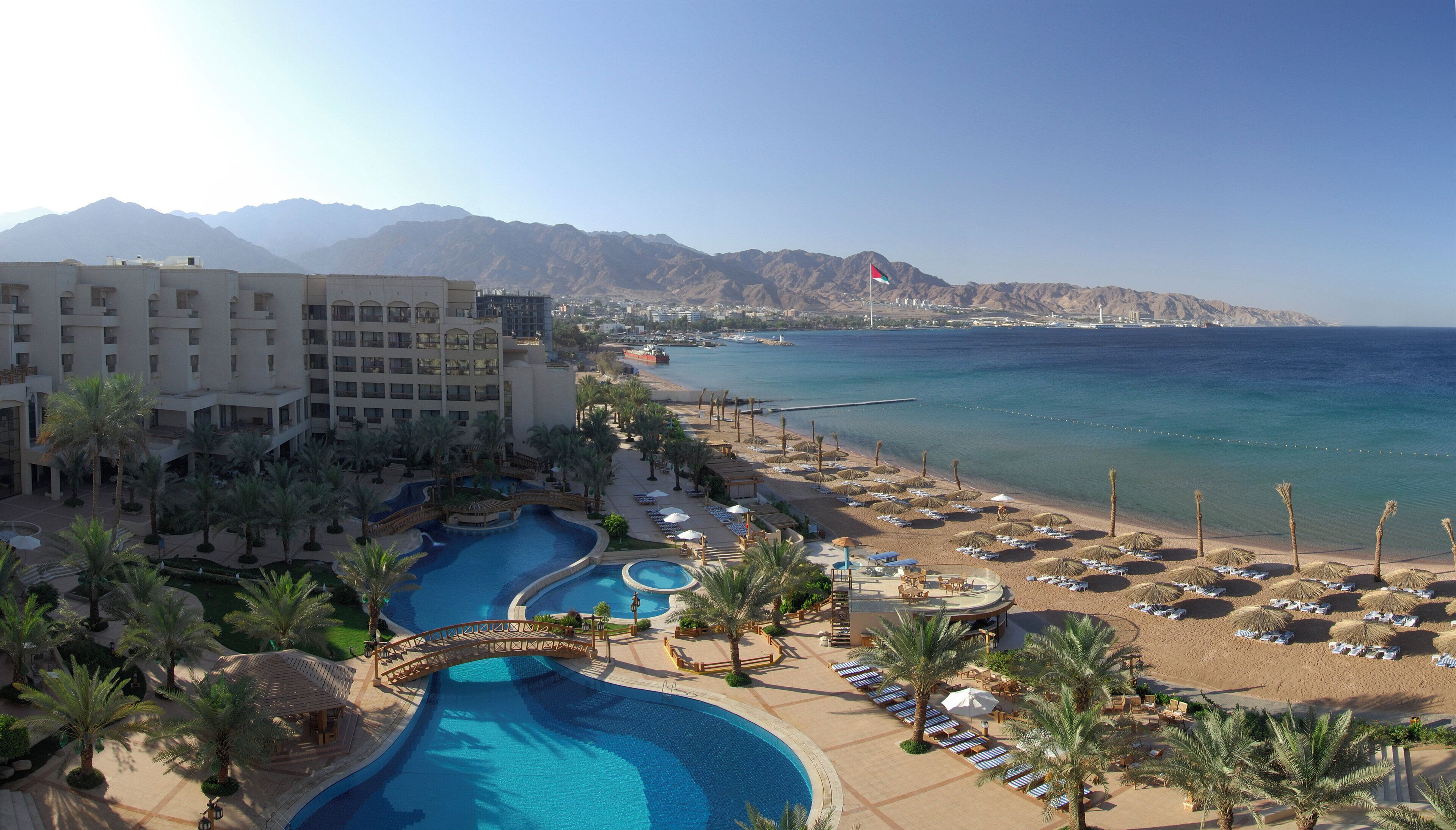 Un complexe hôtelier doté d’une grande piscine, d’une plage et offrant une vue sur les montagnes.