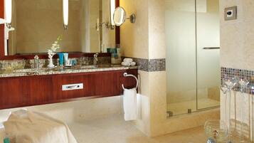 A modern bathroom with a marble vanity, a large mirror, a glass shower enclosure, and a glass-topped vanity.