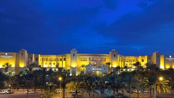 A large hotel with multiple wings, palm trees in the foreground, and a clear sky.