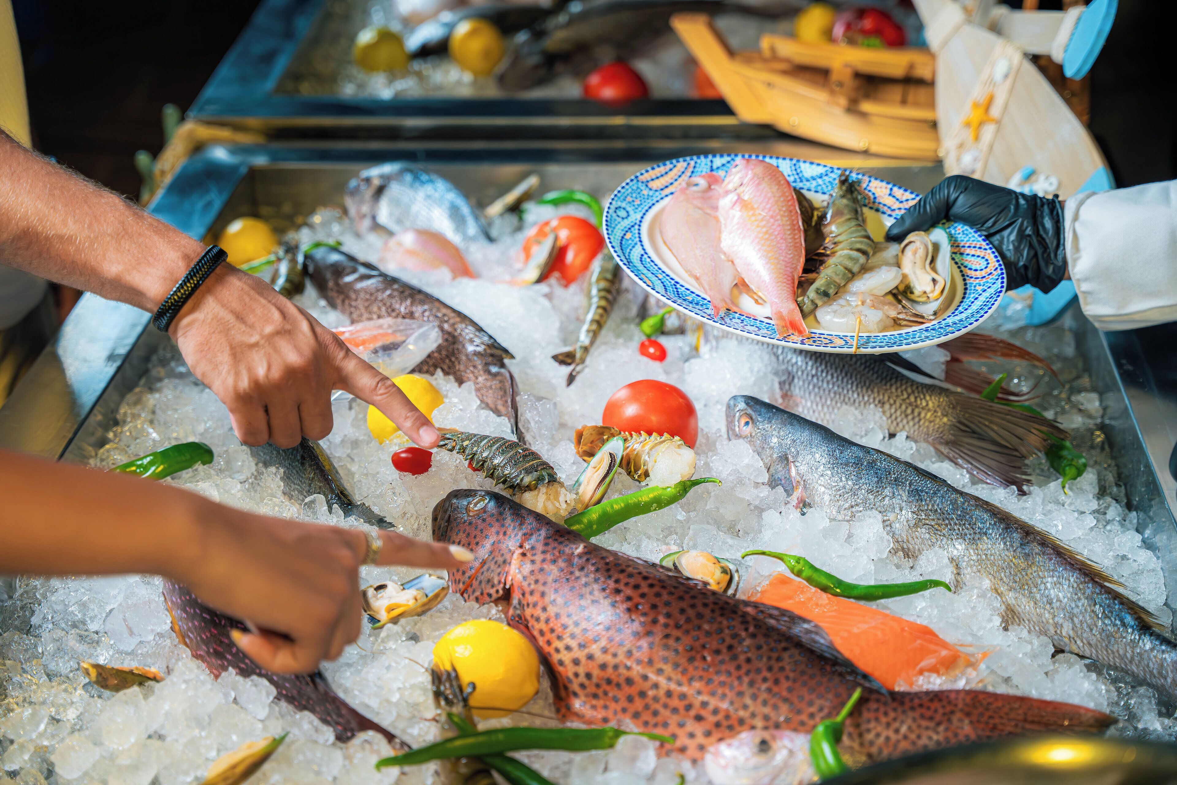 Un assortiment de fruits de mer frais, présentés sur de la glace, avec des citrons, des tomates et des poivrons verts.