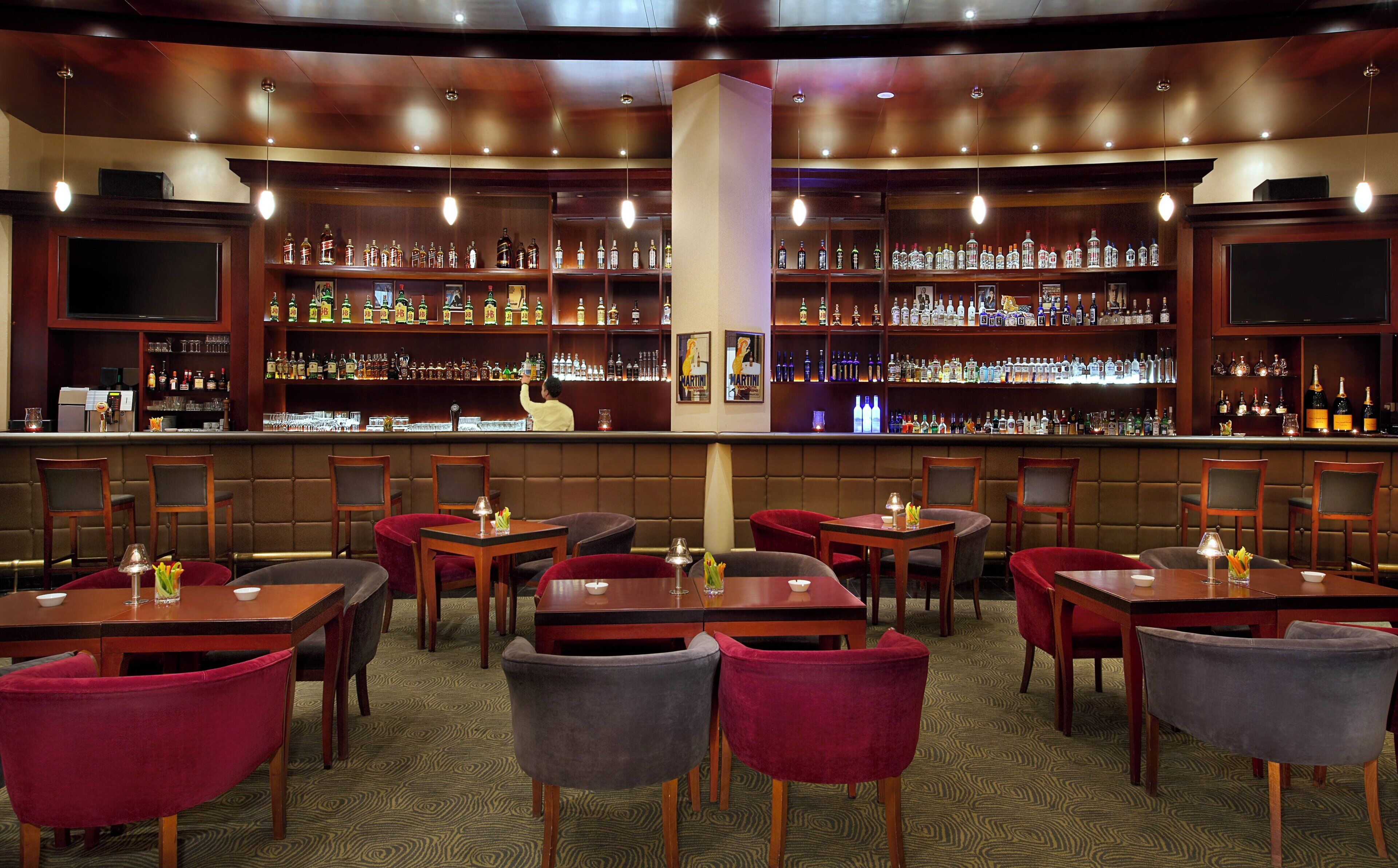 A bar area with multiple seating arrangements and a bartender.