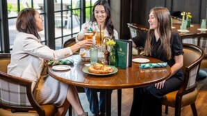 Three people seated at a round table in a restaurant with a menu and drinks. - Saint John's Resort (Plymouth)