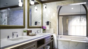A modern bathroom with two sinks, a large mirror, and a window with a view of the outside.