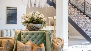 A luxurious living room with a large green sofa, patterned armchairs, a small round table, and a chandelier. - Saint John's Resort (Plymouth)