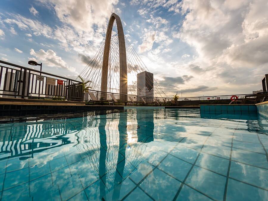 A swimming pool with a view of a large bridge and buildings in the background.