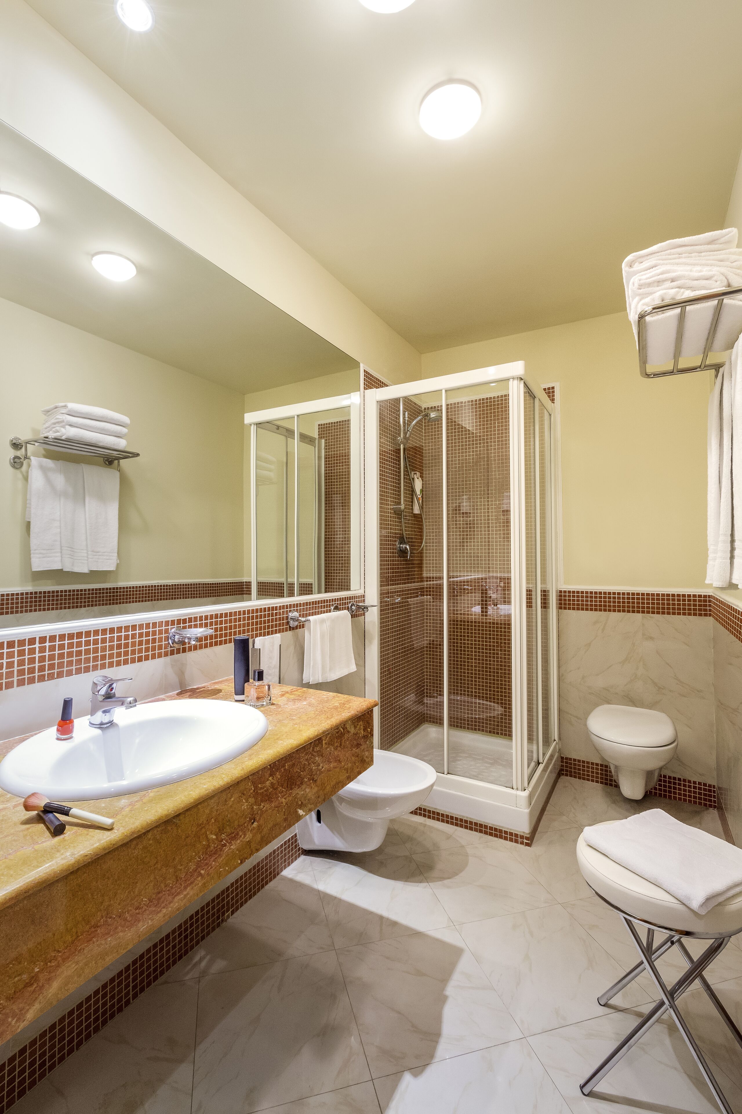 Un baño moderno con ducha de vidrio, lavamanos con encimera de mármol y retrete.