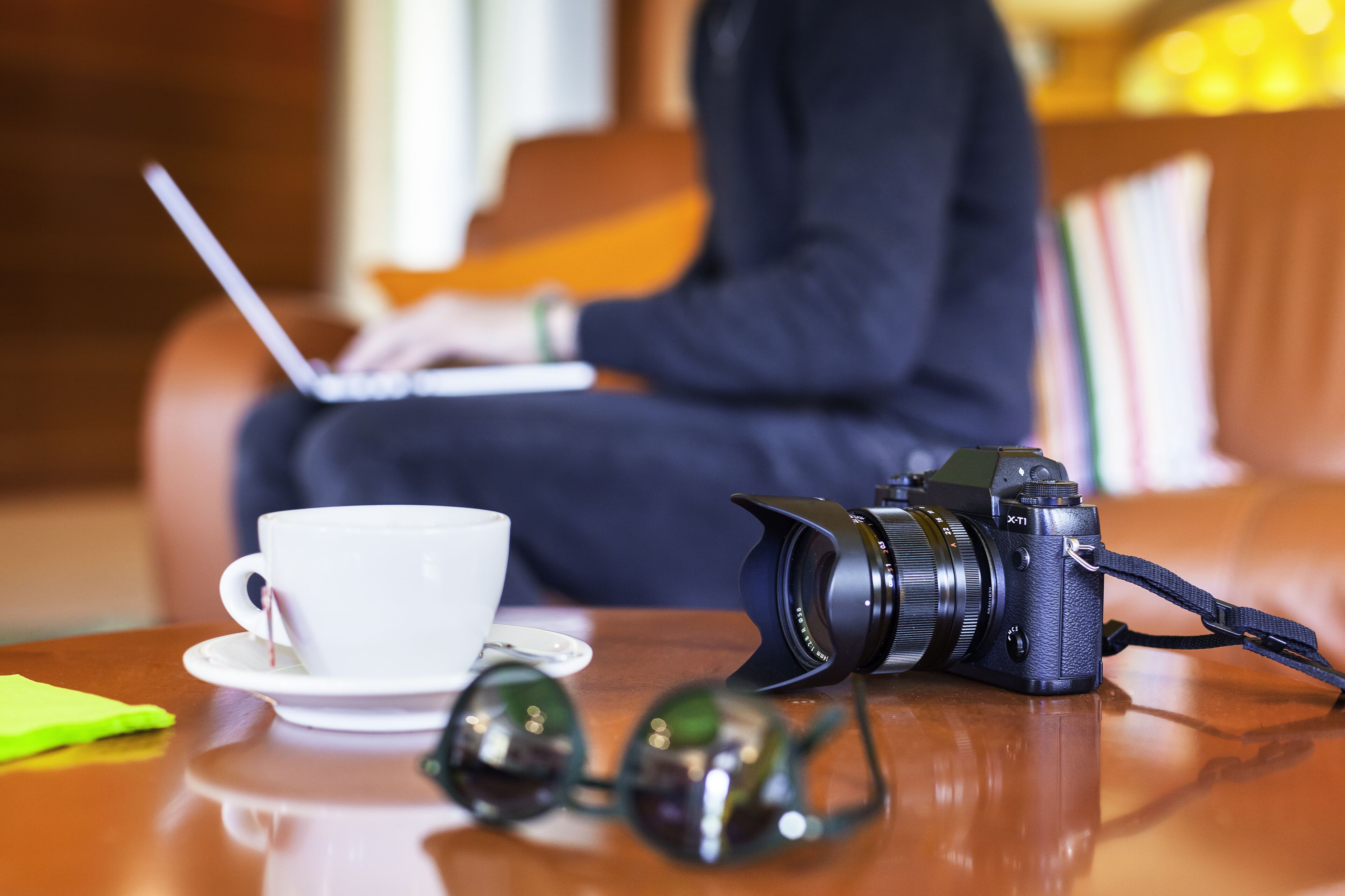 A camera, a cup, and a pair of glasses on a table.