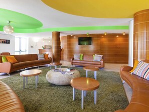 Un salon moderne avec des canapés en cuir, des tables basses rondes et un tapis vert.