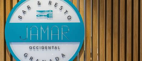 A circular sign with the words "BAR & RESTO JAMAR OCCIDENTAL GRANADA" and a fork and knife graphic.