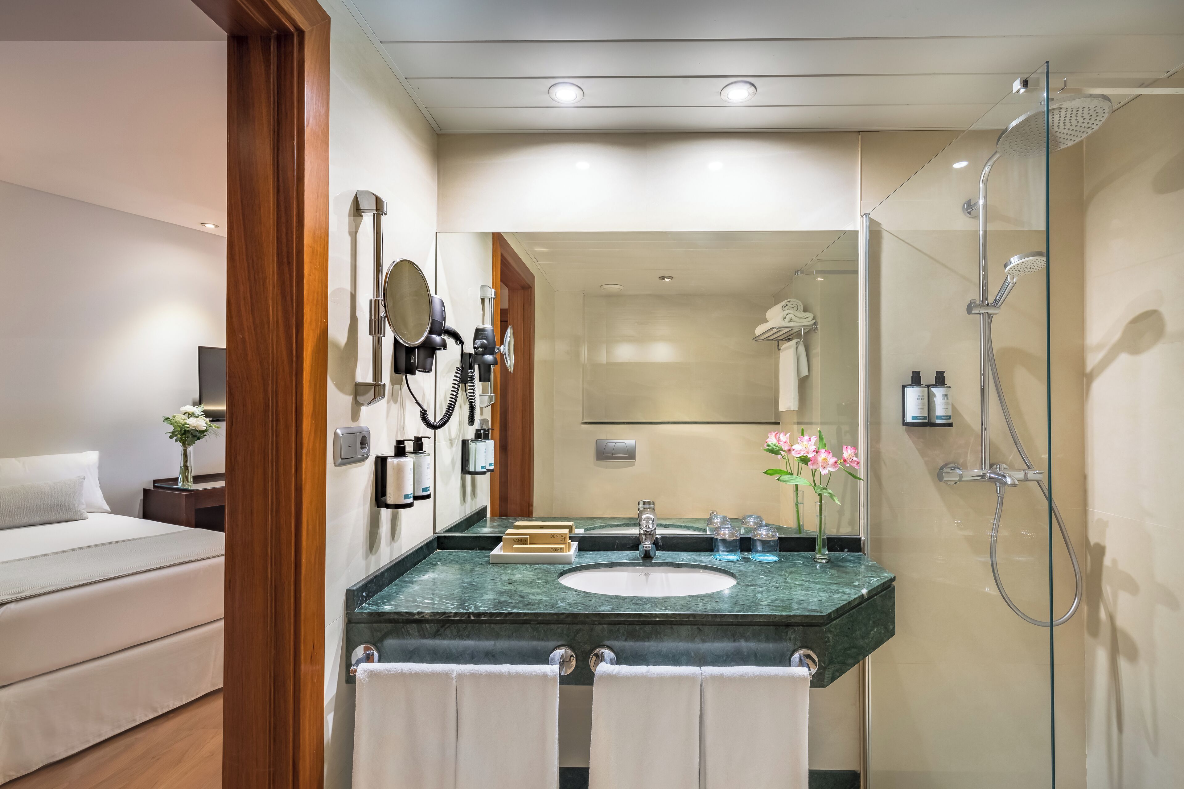 Un bagno moderno con cabina doccia in vetro, lavabo in marmo e uno specchio.