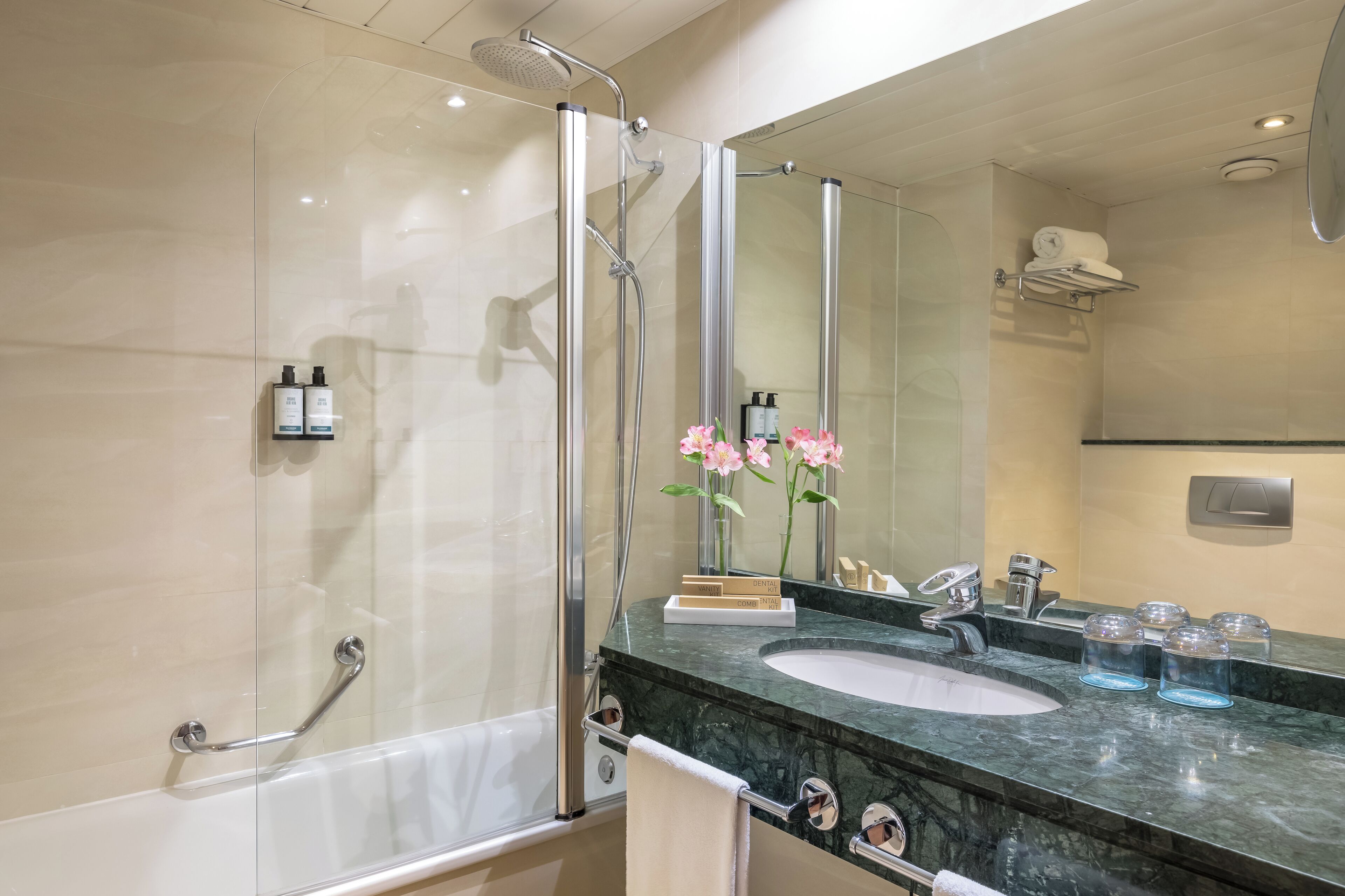 A modern bathroom with a glass-enclosed shower, a large mirror, a marble sink, and a towel rack.