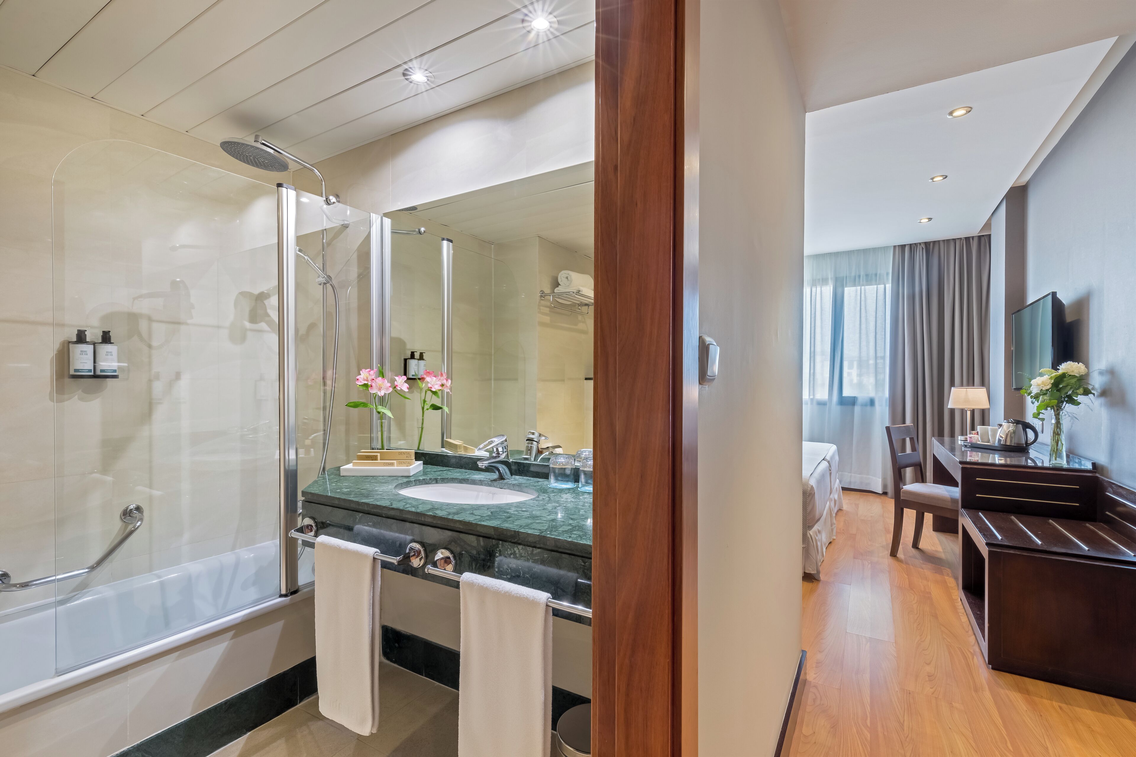 Une salle de bain moderne avec une douche à parois de verre, un lavabo en marbre et un meuble-lavabo avec un miroir.