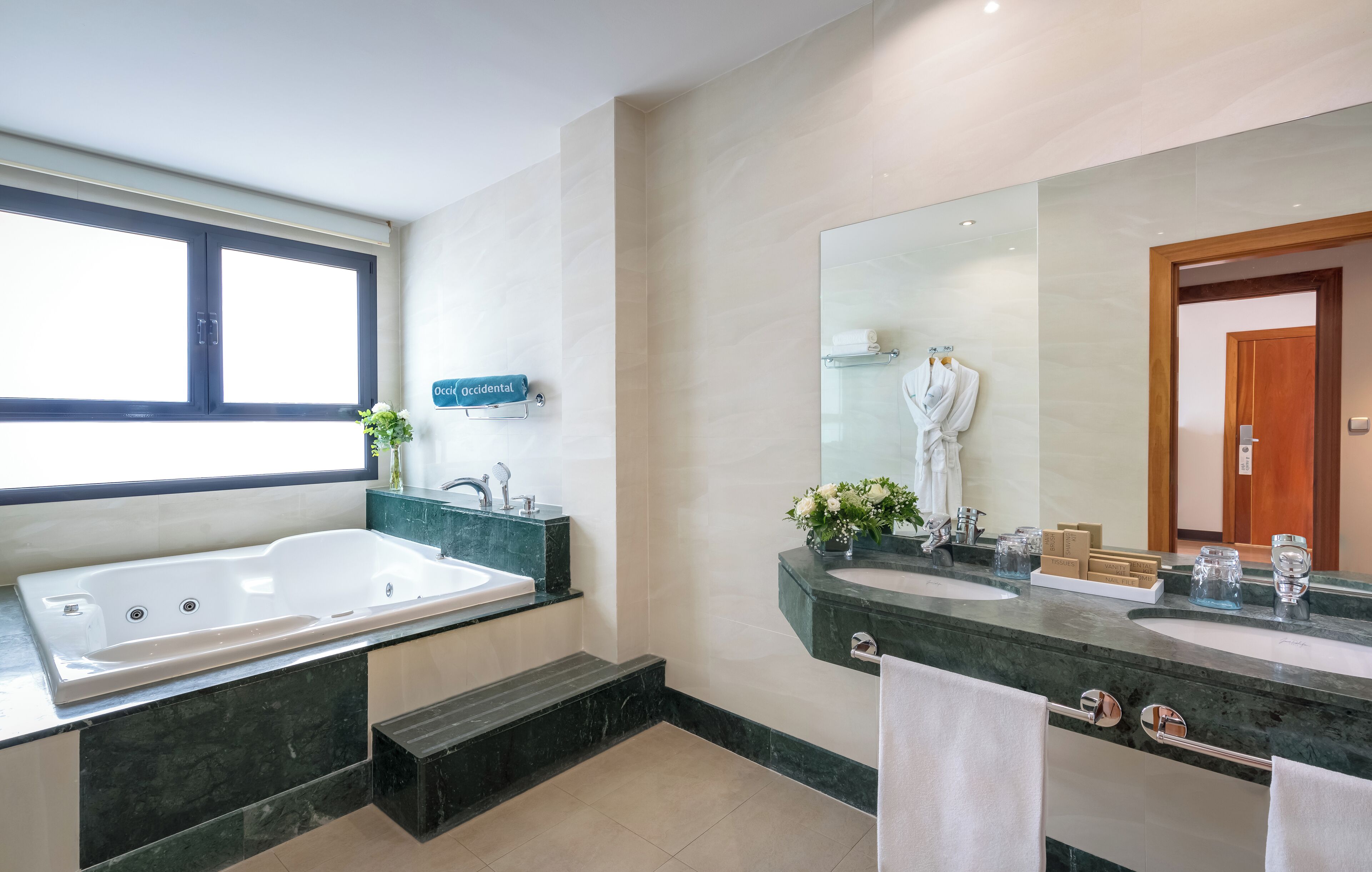 Un baño moderno con una bañera grande, dos lavamanos y un espejo amplio.