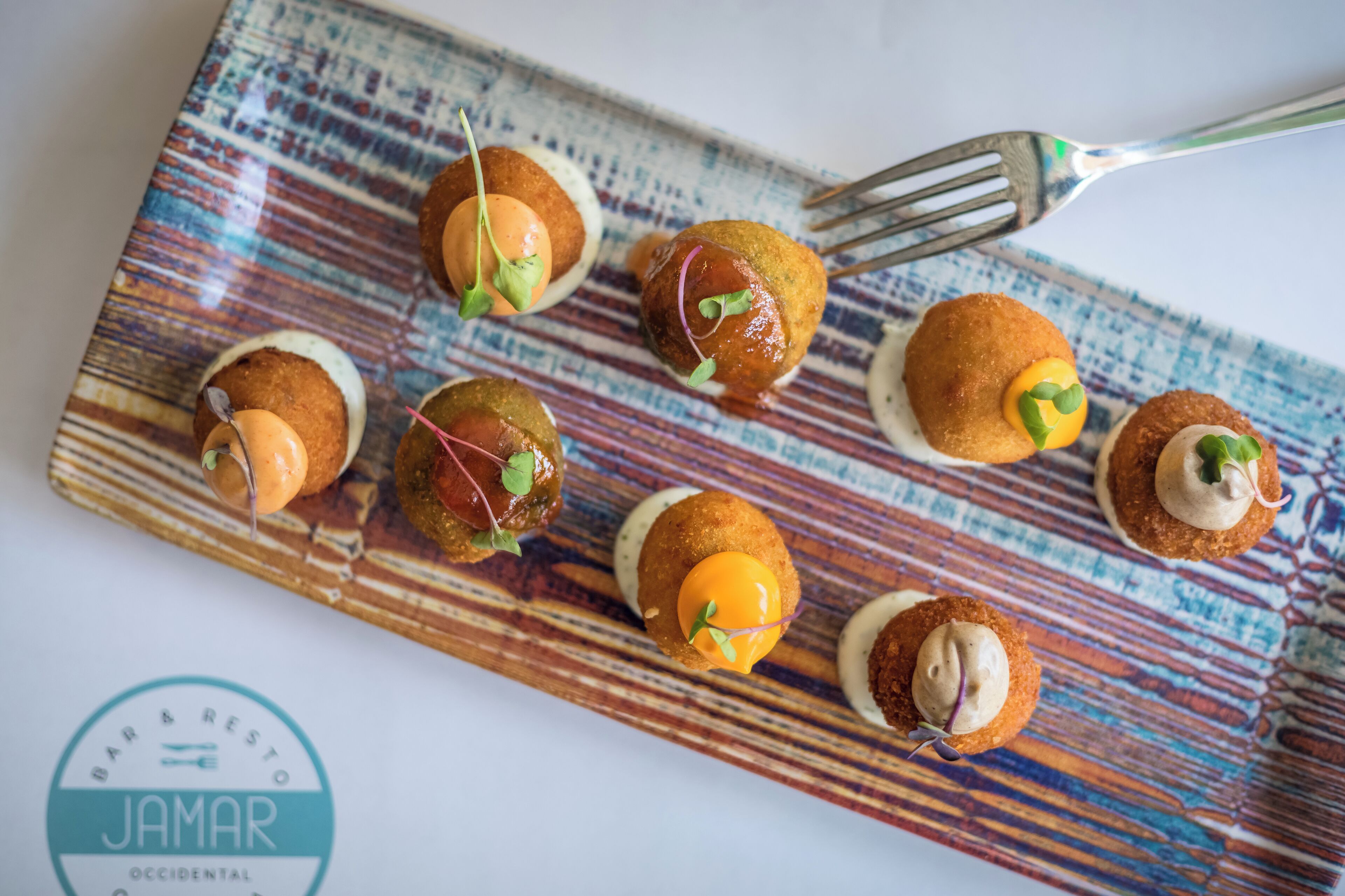 Un plato de aperitivos con un tenedor sobre una mesa estampada.
