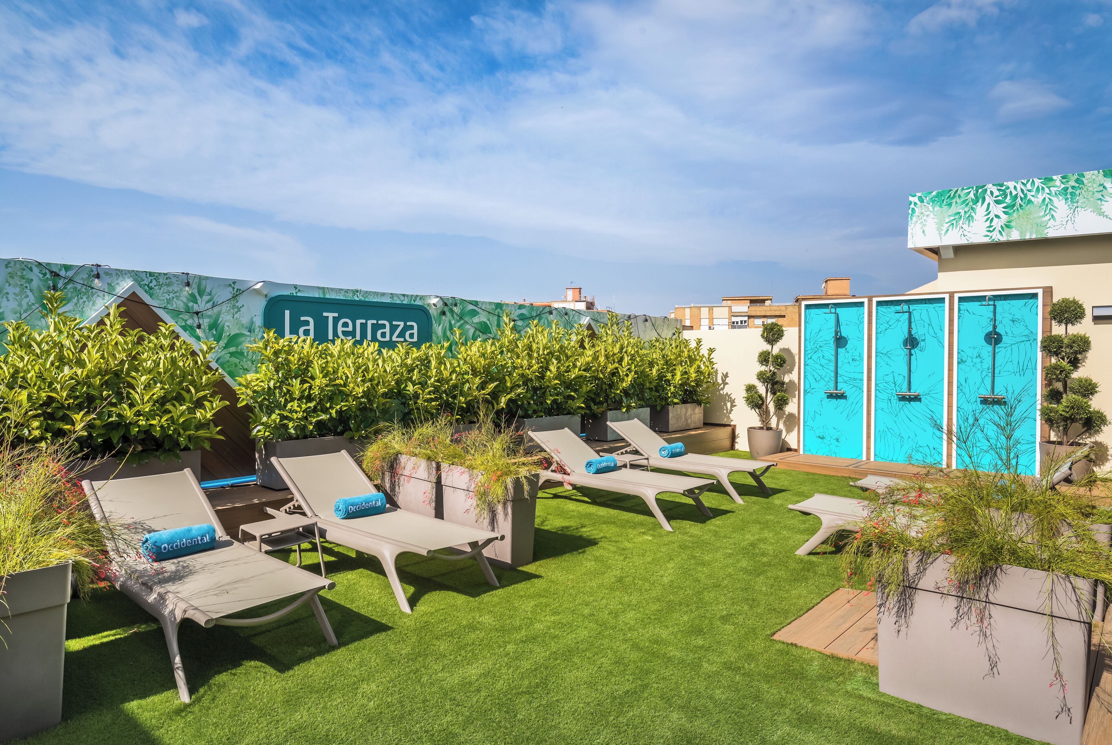 Un jardín en la azotea con sillones de descanso, un letrero que dice 'La Terrazza' y una puerta azul con ducha.
