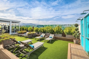 En takträdgård med solstolar, en skylt med texten ”La Terrazza”, och utsikt över avlägsna berg.