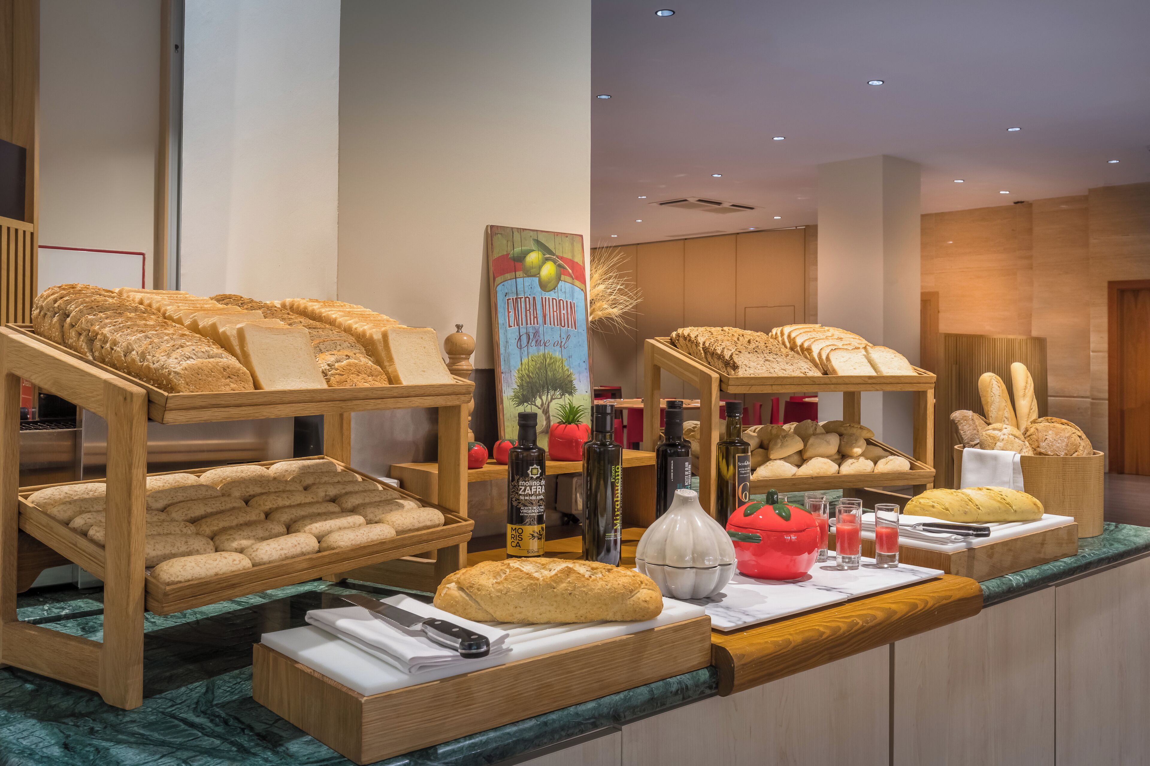 A buffet area with various breads, a bottle of olive oil, and condiments.