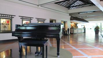 A grand piano in a spacious lobby with tiled flooring and a high ceiling.