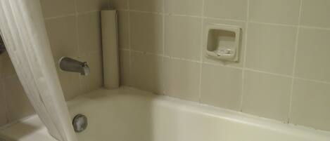 A bathroom with a bathtub, a shower curtain, a towel, and a soap dish.