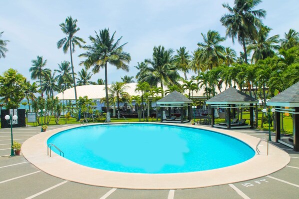 Una gran piscina cristalina rodeada de palmeras y estructuras cubiertas.