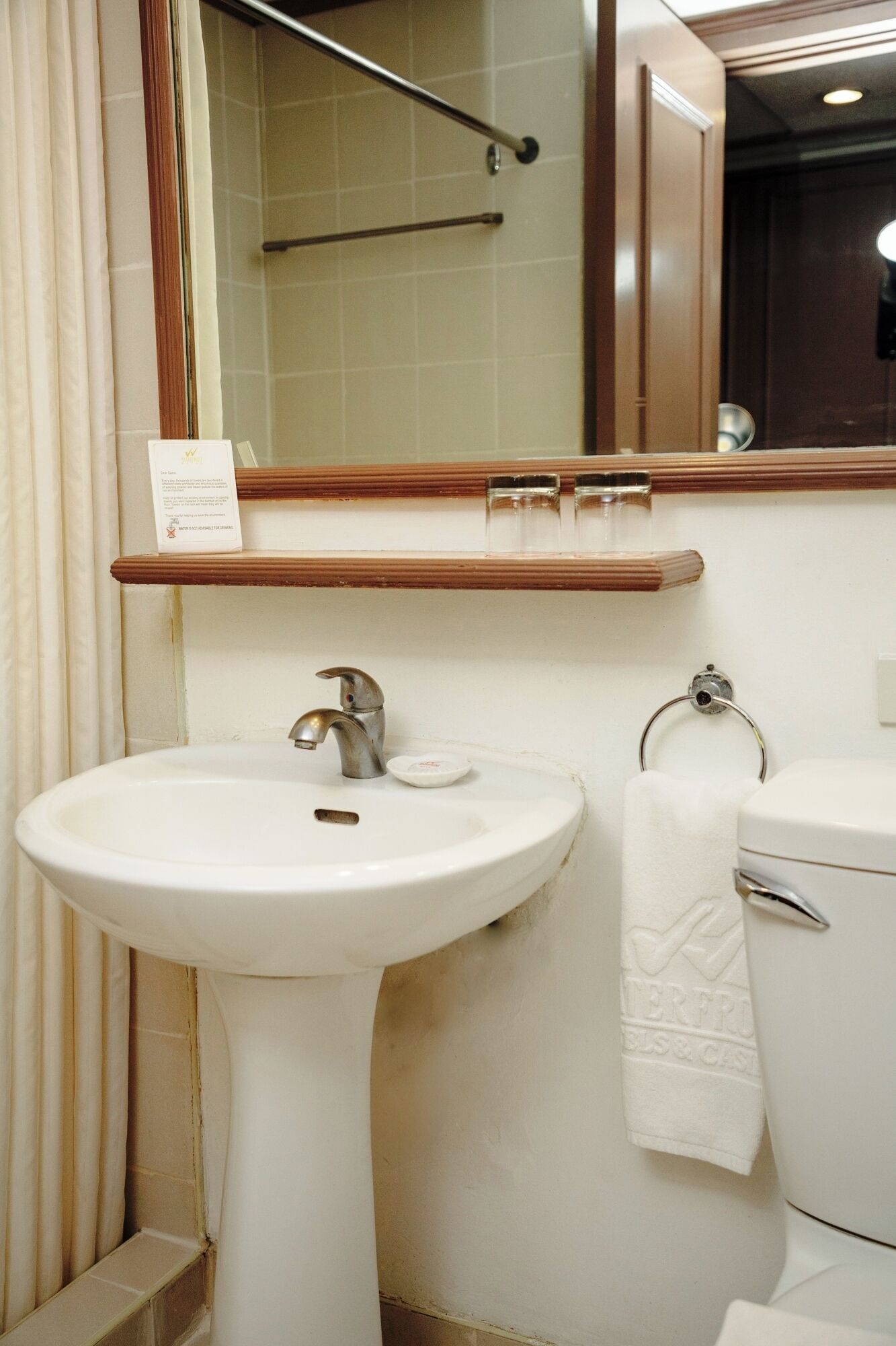 A bathroom with a white sink, a mirror, a towel rack, and a toilet.