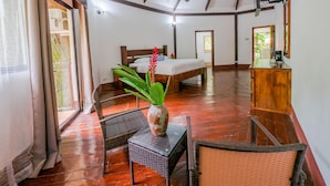 A spacious room with a wooden floor, a bed, a desk, and a chair. - Villa Lapas Jungle Village (Tárcoles)