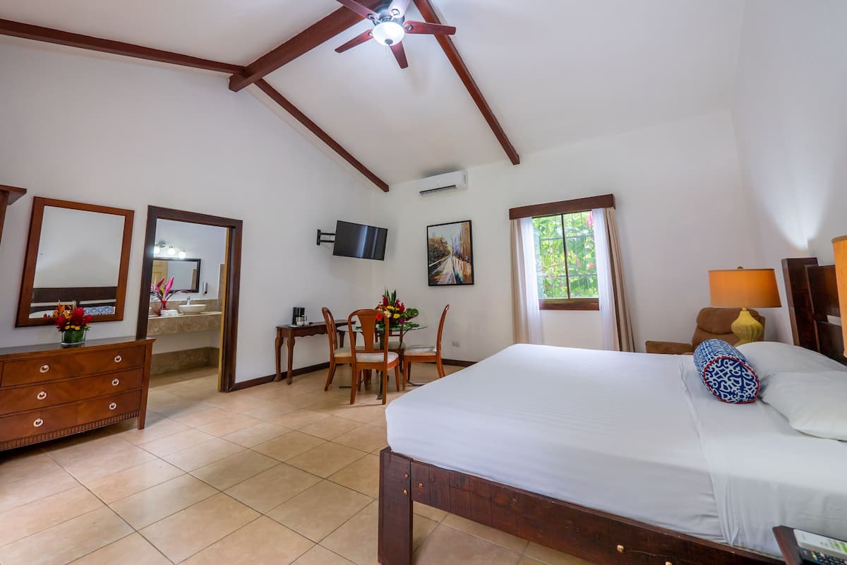 Une chambre d’hôtel comprenant un lit, un bureau avec une chaise, une télévision et une fenêtre avec des rideaux.