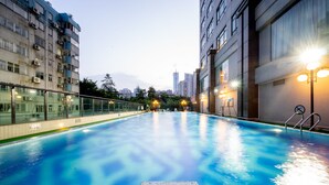 An indoor swimming pool with a tiled floor, surrounded by high-rise buildings and a cityscape in the background. - Guangzhou Grand International Hotel (Guangzhou)