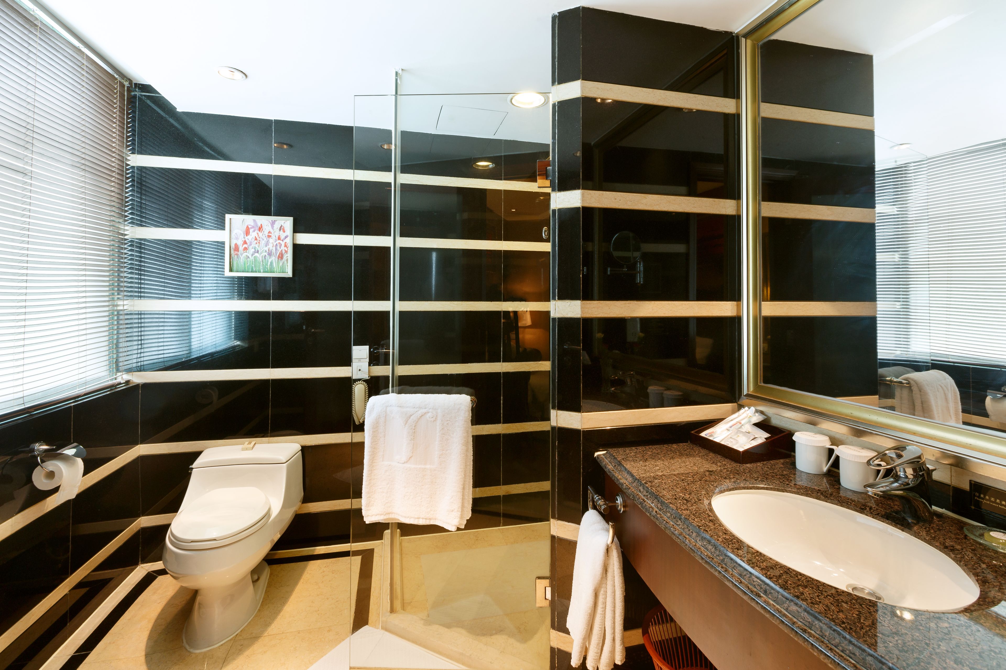 A modern bathroom with a large mirror, a sink, and a toilet.