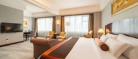 Habitación de hotel con una cama grande, dos sillones, un escritorio, un televisor de pantalla plana y un cuadro en la pared.