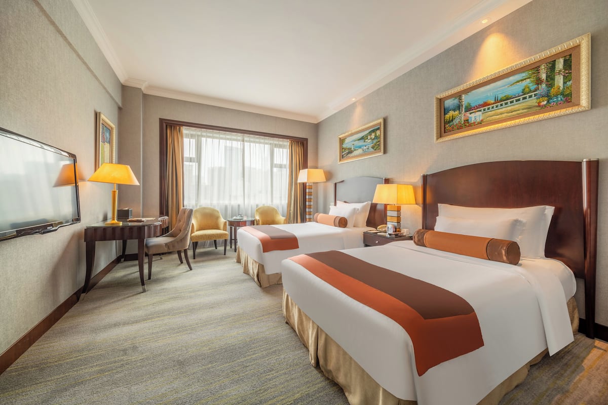 Ein Hotelzimmer mit zwei Betten, einem Schreibtisch, einem Stuhl und einem Fernseher.