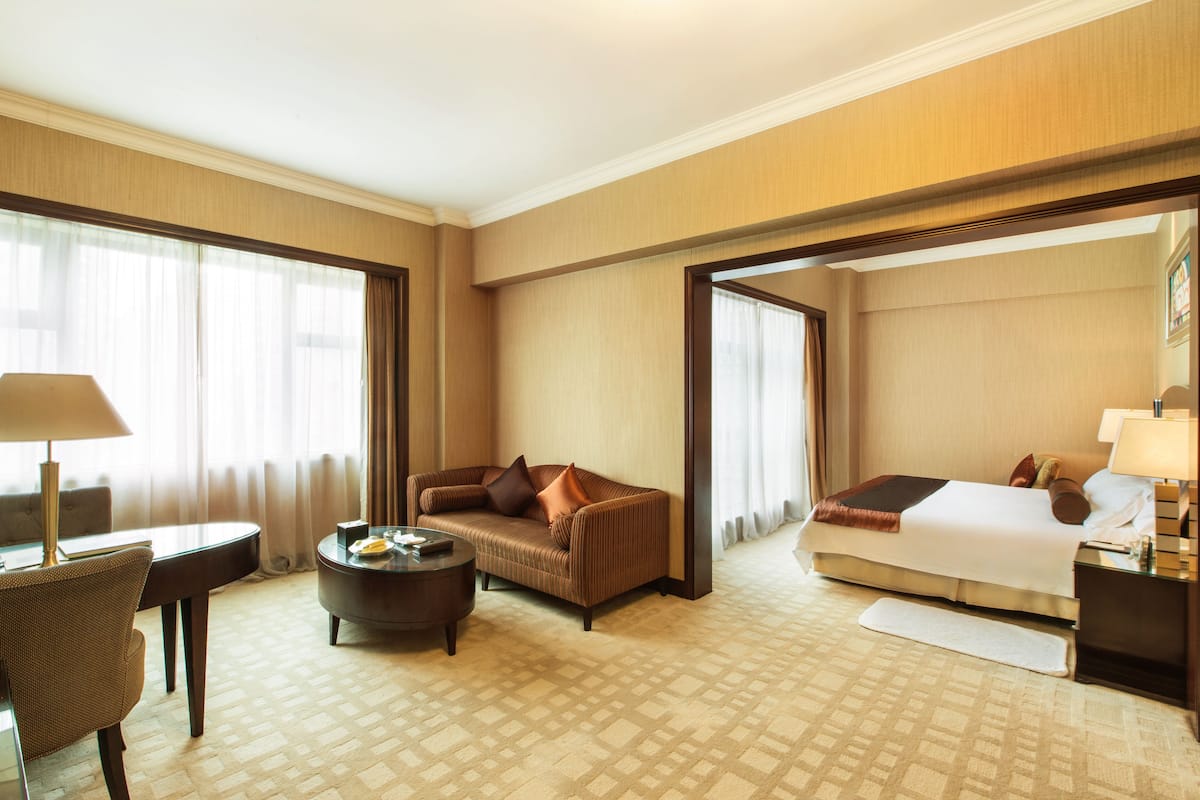Ein Hotelzimmer mit einem Bett, einem Sofa, einem Couchtisch, einem Schreibtisch und einem Sessel.