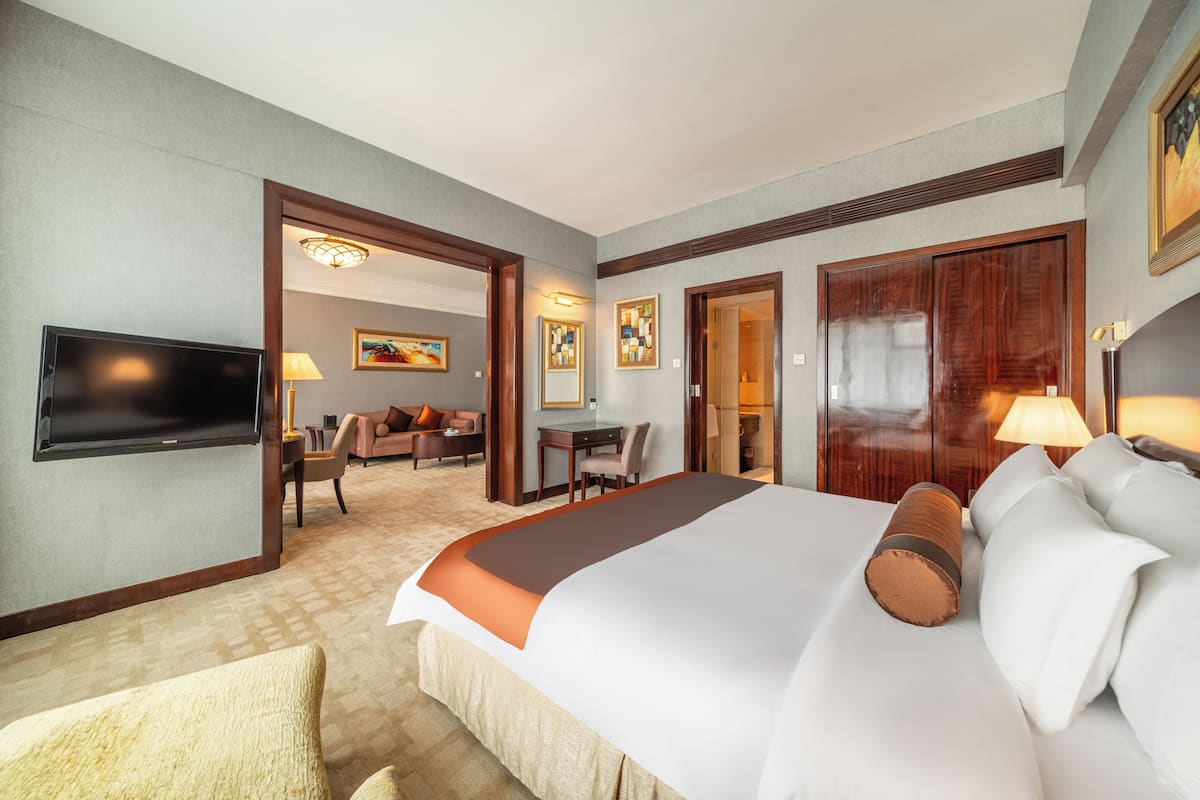 Ein Hotelzimmer mit einem großen Bett, einem Fernseher, einem Schreibtisch und einem Sessel.