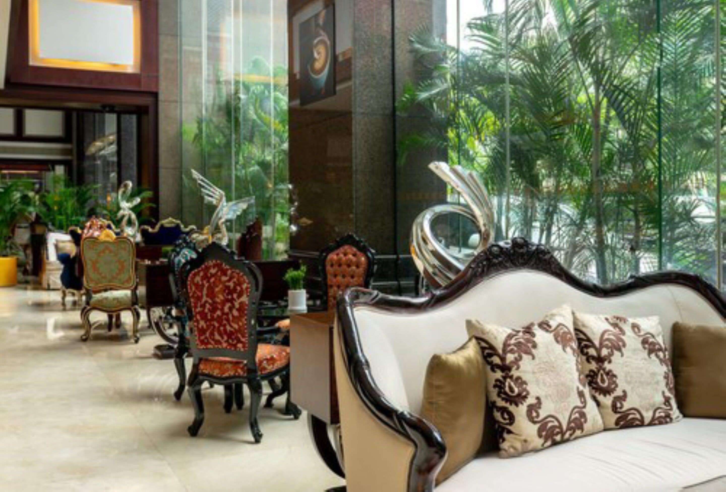 A lobby with a sofa, chairs, and a large window with a view of greenery.
