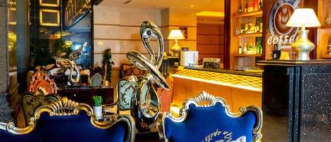 A bar area with ornate chairs, a counter with a coffee theme, and a decorative mirror.