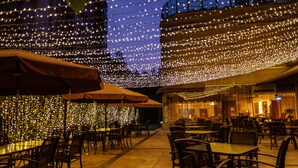 An outdoor dining area with tables and chairs, string lights, and umbrellas. - Guangzhou Grand International Hotel (Guangzhou)