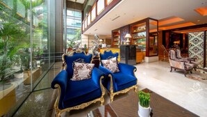 A spacious lobby with a glass wall, a blue sofa set, a coffee table, and a bookshelf. - Guangzhou Grand International Hotel (Guangzhou)