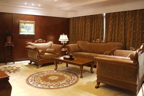 Ein Wohnzimmer mit einer Sofagarnitur, einem Couchtisch und einem gemusterten Teppich.