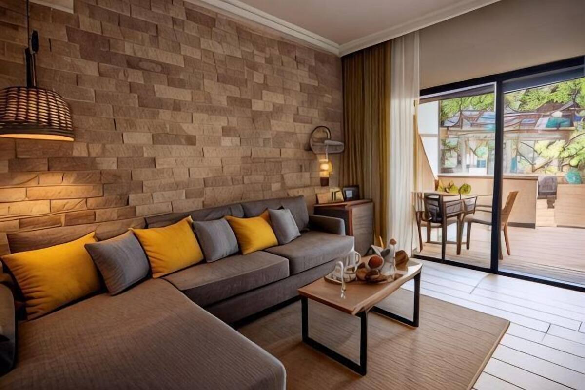 A modern living room with a sectional sofa, a coffee table, and a view through a glass door to an outdoor area.