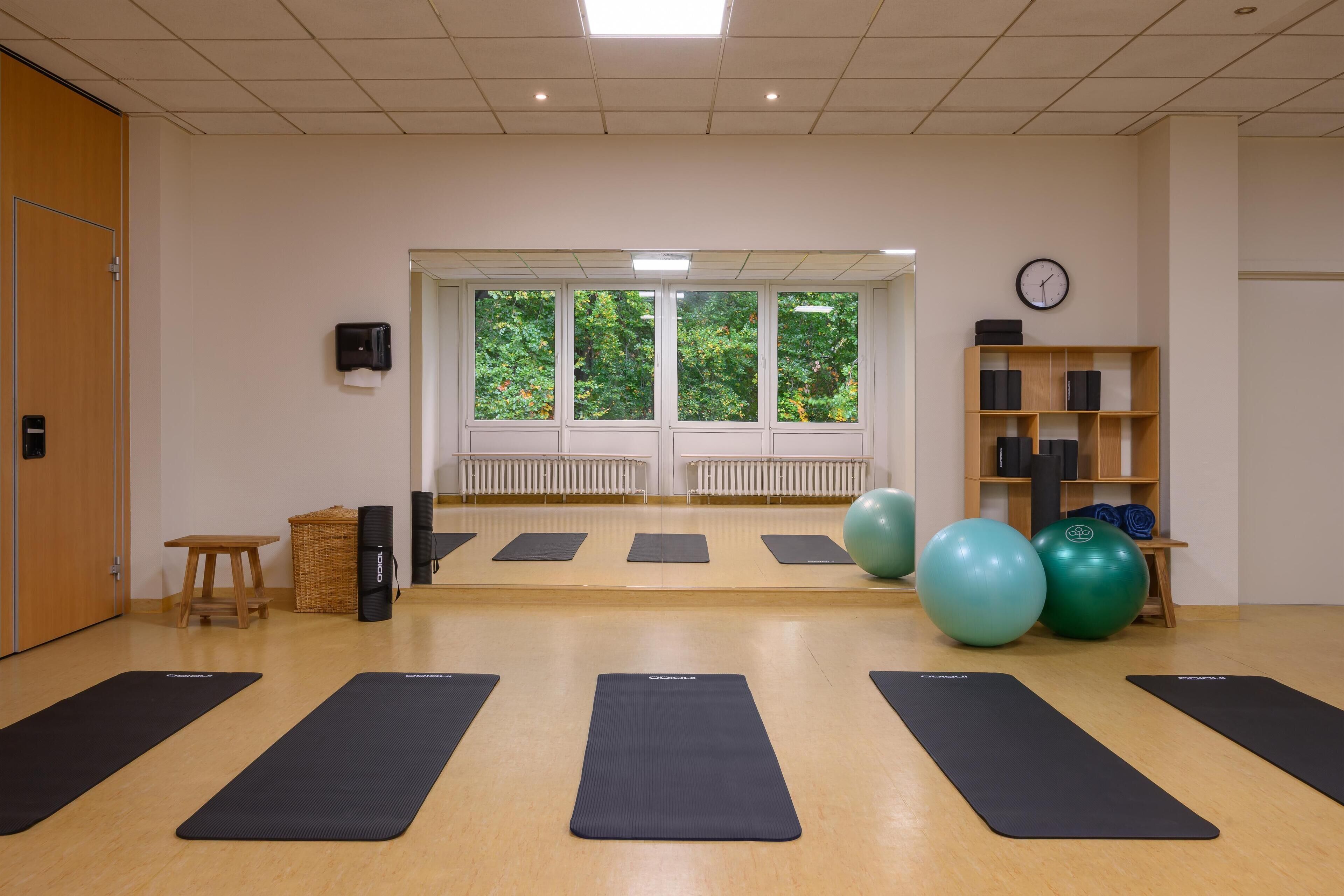Ein Yogastudio mit schwarzen Matten, Holzmöbeln und Trainingsbällen.