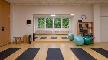 Ein Yogastudio mit schwarzen Matten, Holzmöbeln und Trainingsbällen.
