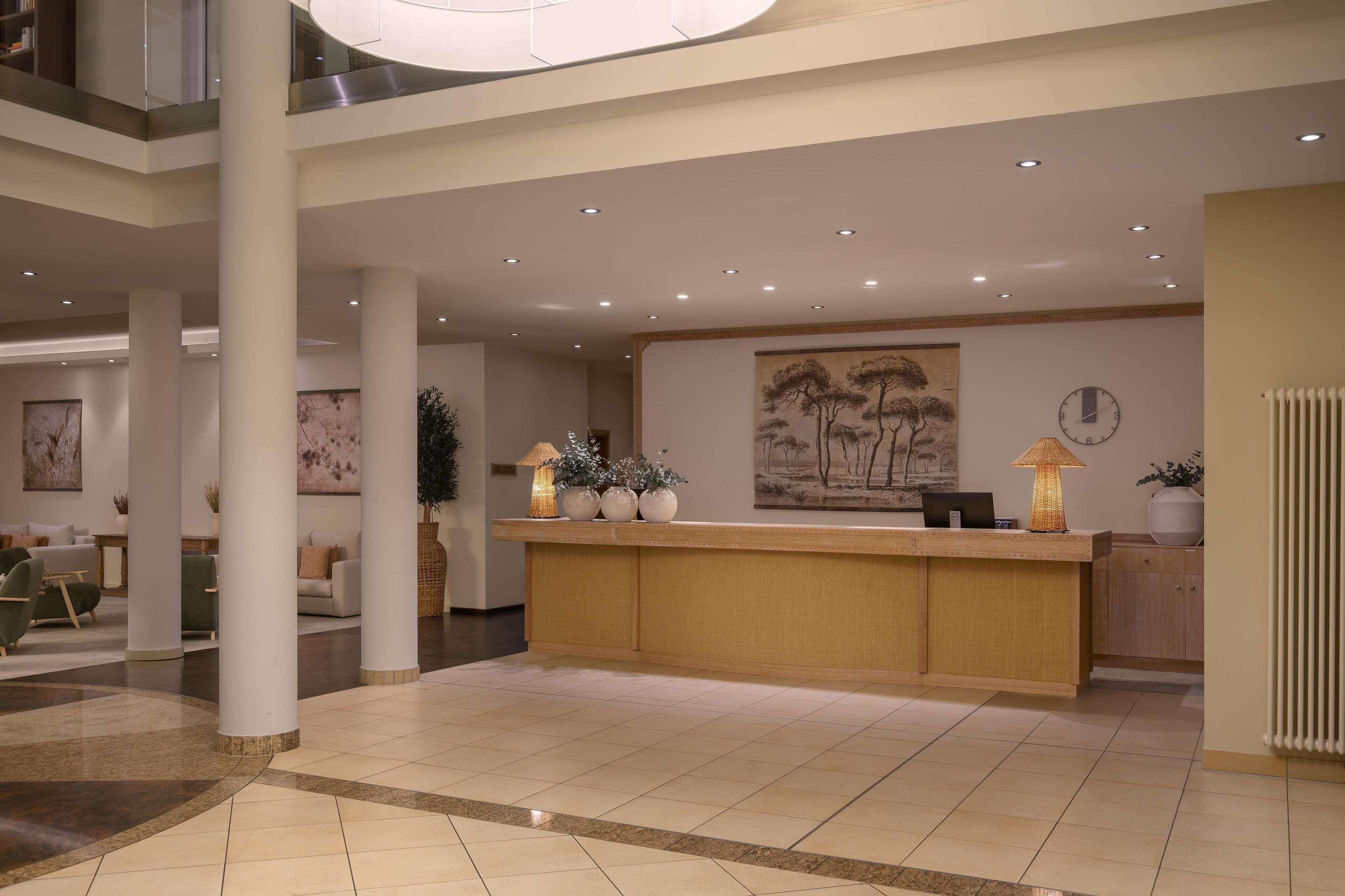 A spacious lobby with a reception desk, seating area, and artwork on the walls.