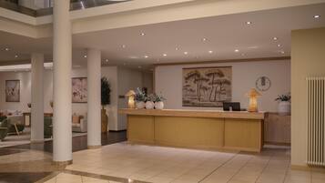 A spacious lobby with a reception desk, seating area, and artwork on the walls.