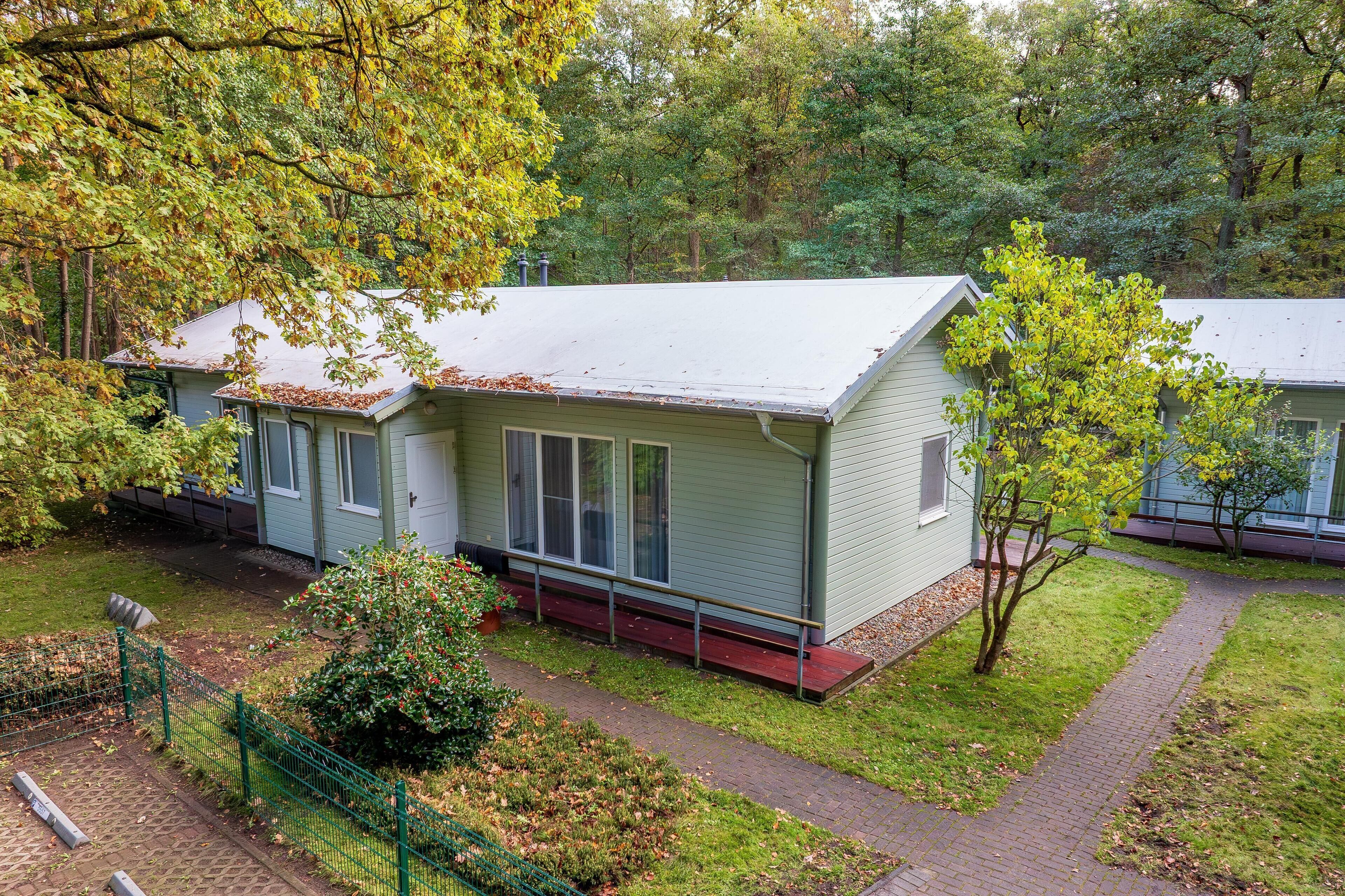 Een klein, gelijkvloers huis met een rode veranda en een meterkast pad dat naar de ingang leidt.
