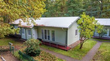 Een klein, gelijkvloers huis met een rode veranda en een meterkast pad dat naar de ingang leidt.