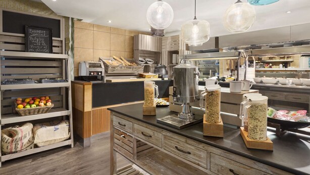 Cozinha moderna com armários de madeira, bancada preta e luminárias pendentes.