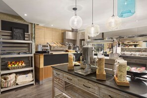 A modern kitchen with wooden cabinets, a black countertop, and hanging pendant lights.