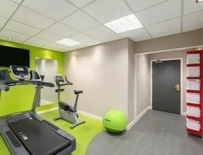 A gym with treadmills, stationary bikes, and a green exercise ball. - Ramada Hotel & Suites by Wyndham Coventry (Coventry)