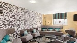 Uma sala de estar moderna com parede estampada, um conjunto de sofá e uma mesa de centro.