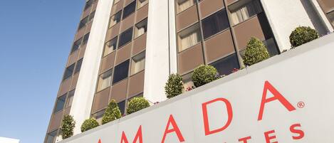 A tall hotel building with a sign reading "RAMADA HOTEL AND SUITES".
